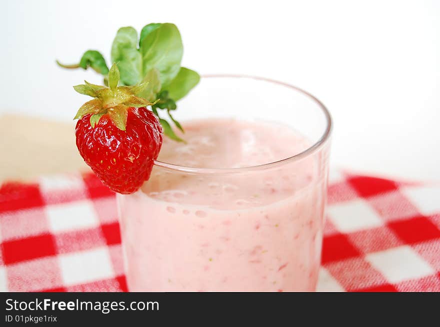 Strawberry cocktail in a glass. Small spoon in a red and white checked napkin.