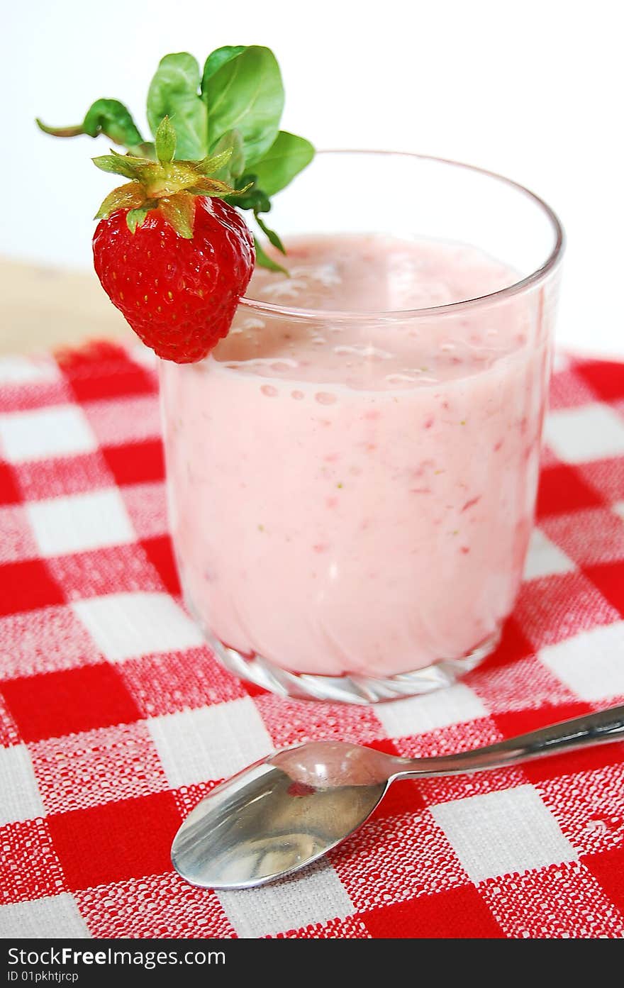 Strawberry cocktail in a glass. Small spoon in a red and white checked napkin