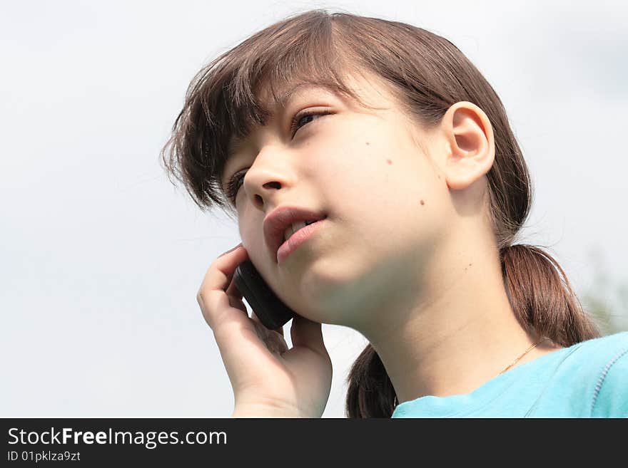 Close-up of nice young girl with mobile phone isolated on sky background. Close-up of nice young girl with mobile phone isolated on sky background