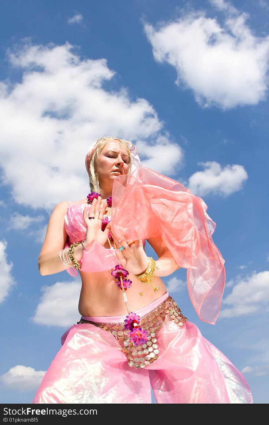 A woman in pink asian dress dancing and a blue sky. A woman in pink asian dress dancing and a blue sky