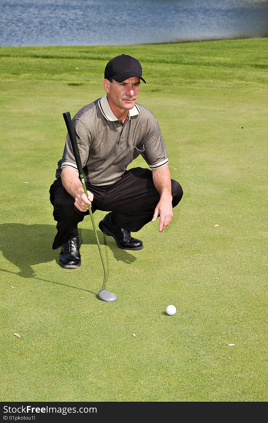 A well-dressed male golfer sizing up his next putt. A well-dressed male golfer sizing up his next putt.