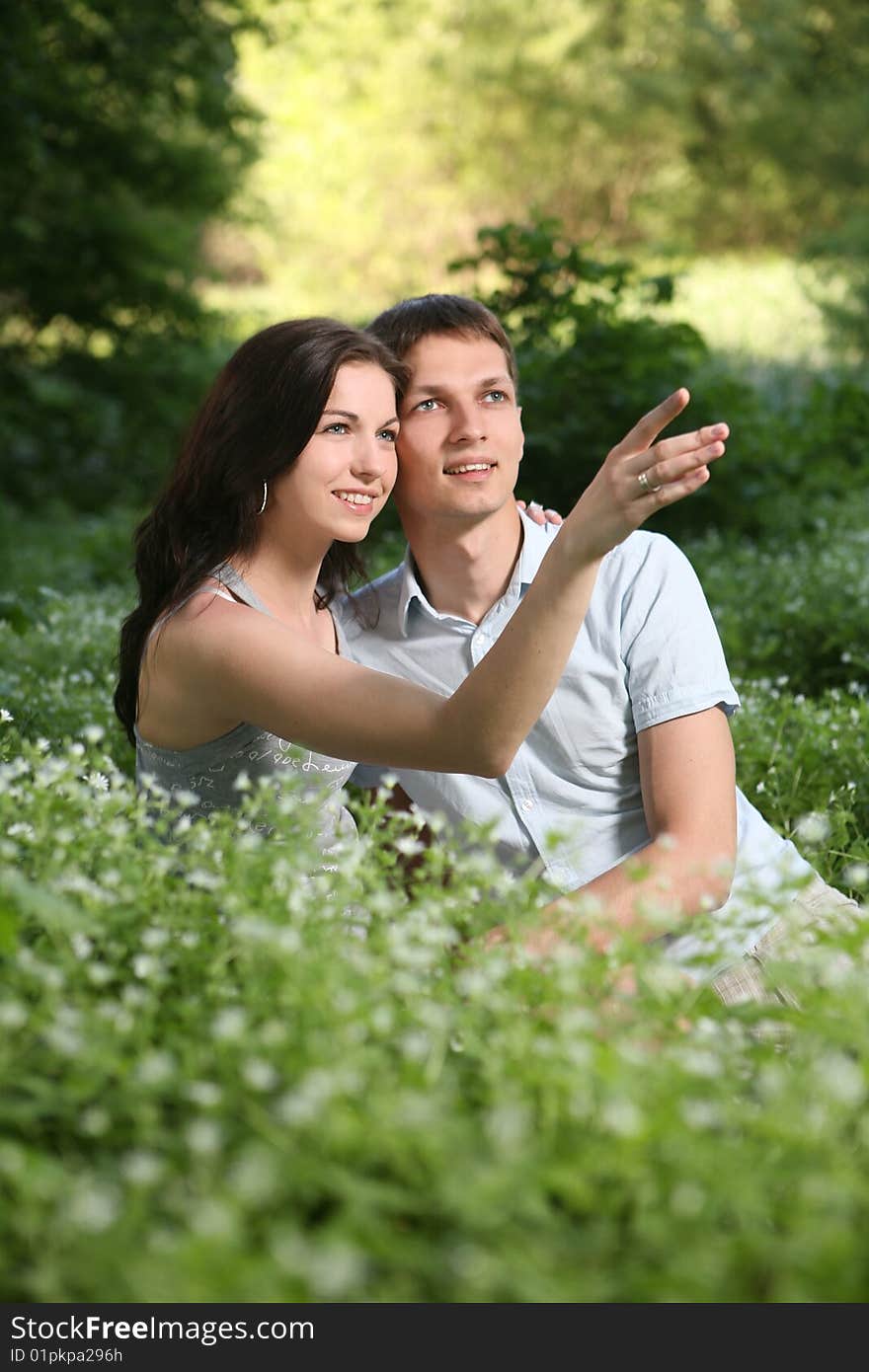 Man and woman sitting on the grass. Looking up. Man and woman sitting on the grass. Looking up.