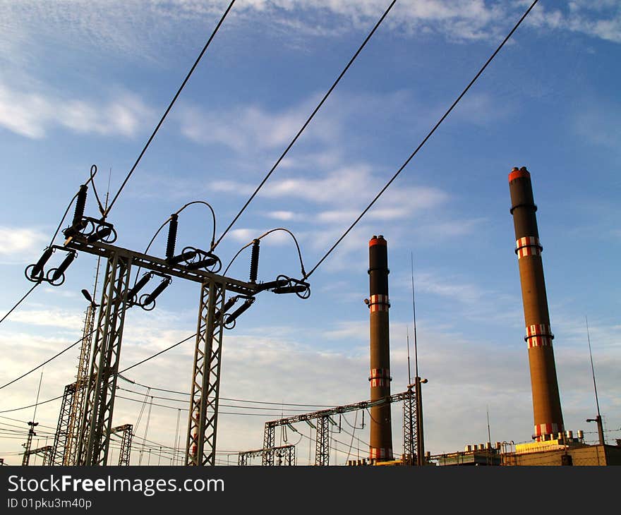 Electric pylon and chimney with blue sky