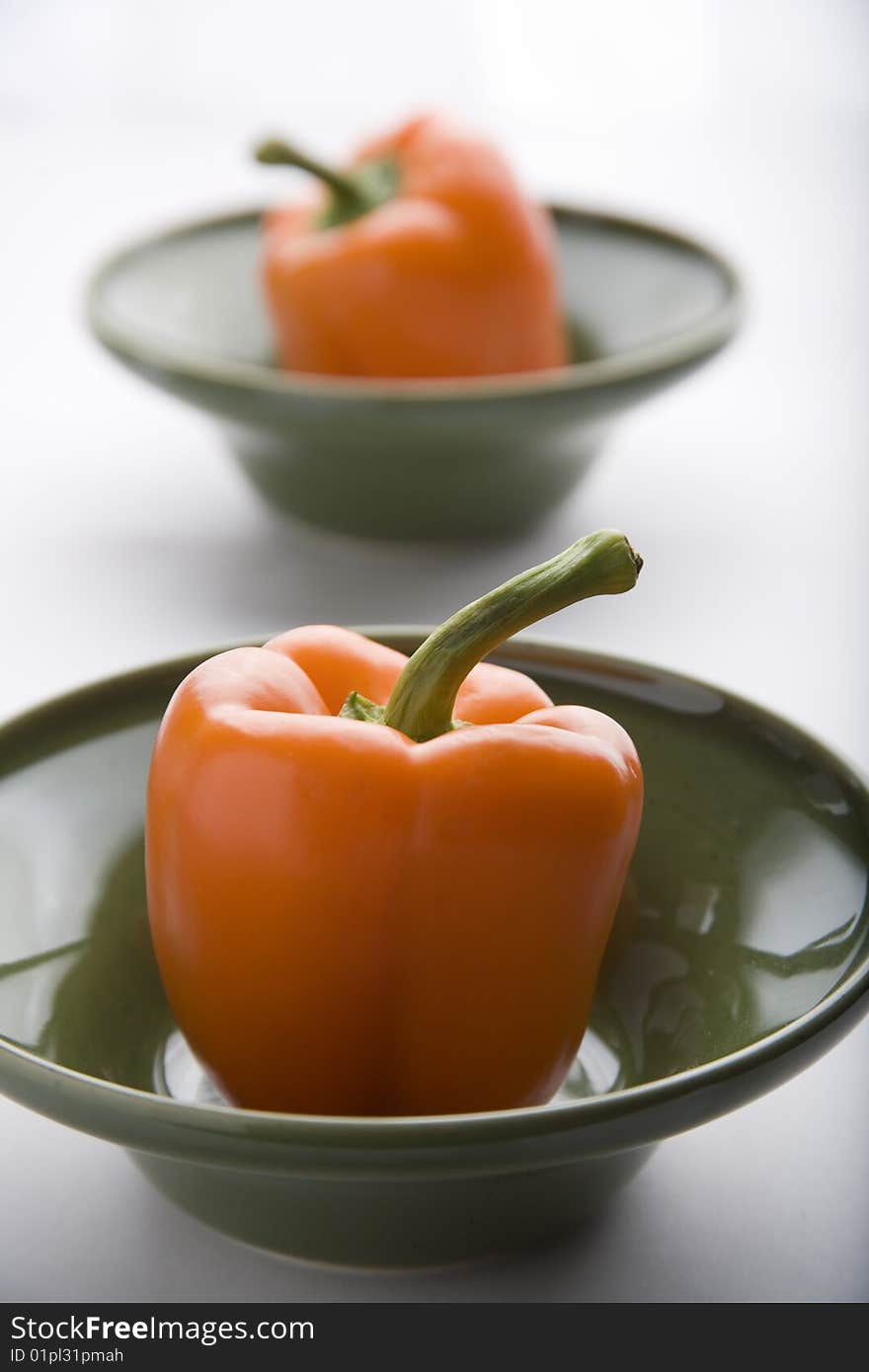 Couple orange peppers on a green bowl