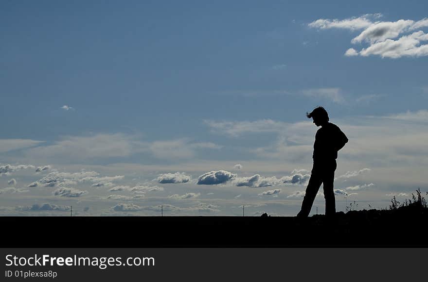 Silhouette of a young man on blue sky background