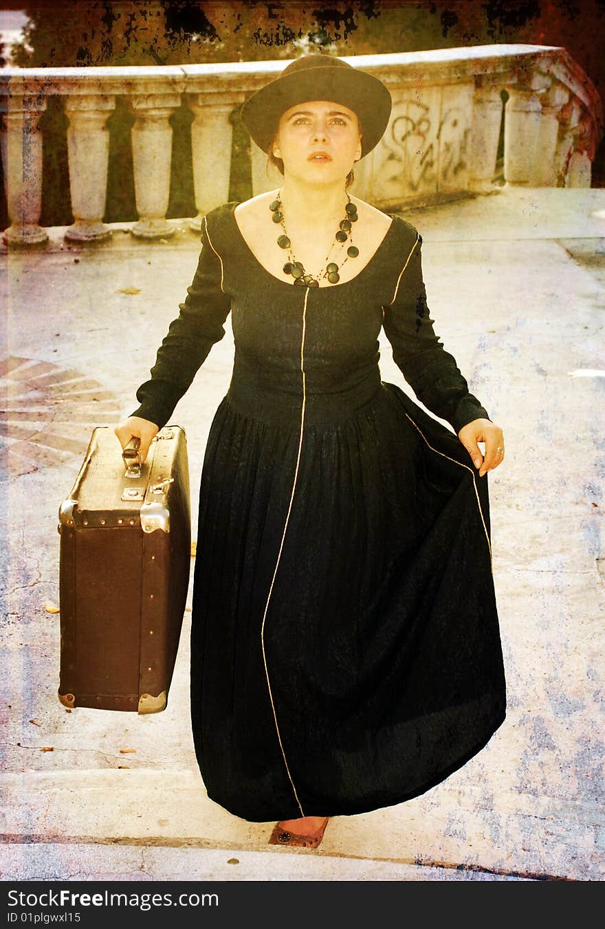 A beauitful girl is staring,looking in front.she wears a black dress and holds an old luggage. A beauitful girl is staring,looking in front.she wears a black dress and holds an old luggage