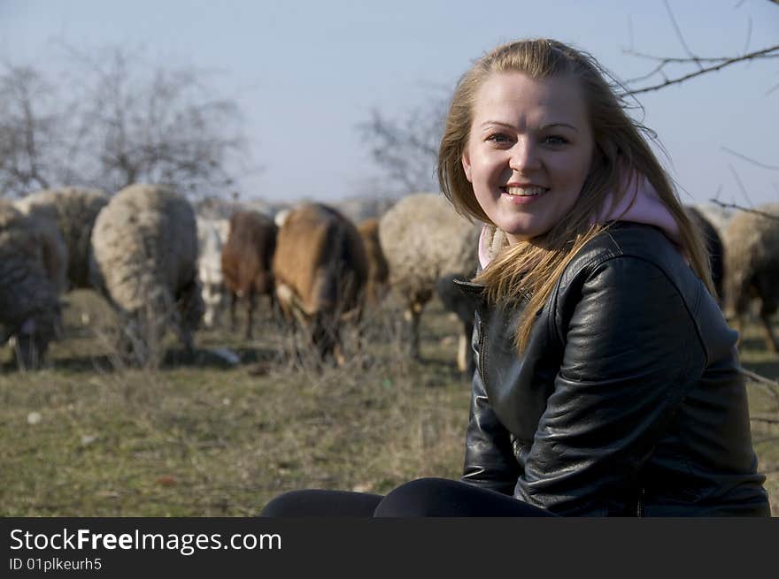 A girl sits on a stone on a background the herd of