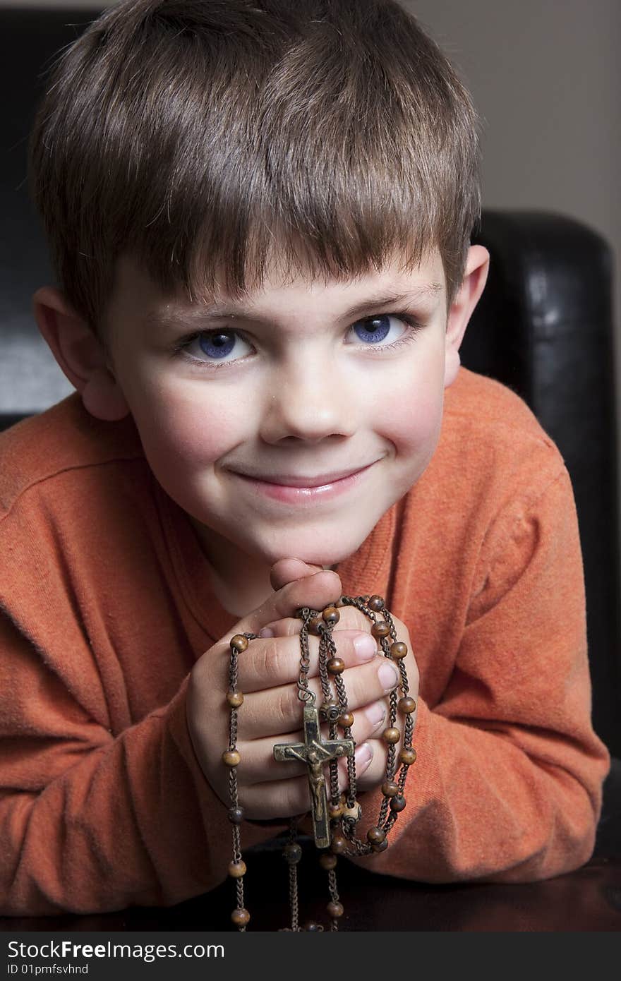 Young boy hold rosery and smiling. Young boy hold rosery and smiling