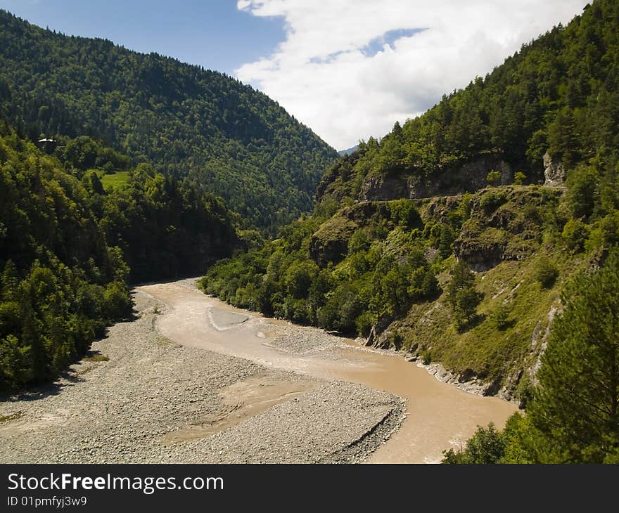 Big valley in Caucasus, Georgia. River blue sky and green forest.