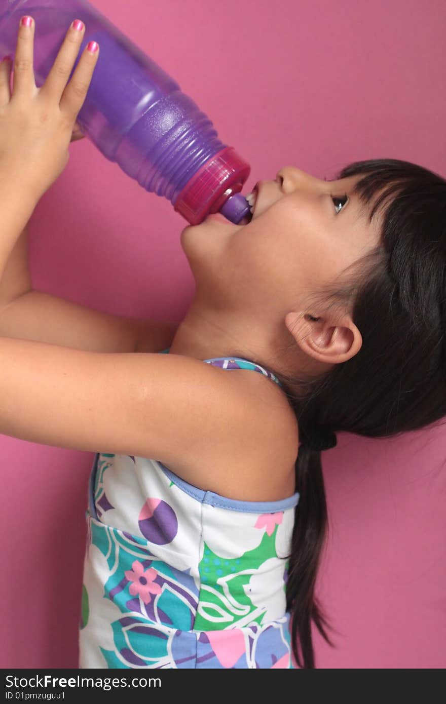 Asian Chinese Girl drinking from a reuseable water bottle with pink back round with head tilted back. Asian Chinese Girl drinking from a reuseable water bottle with pink back round with head tilted back