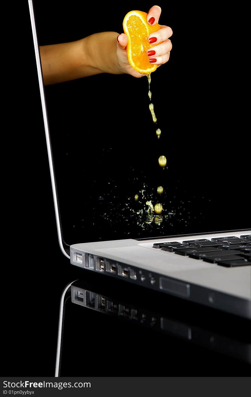 Woman hand squeezing an orange in laptop. Isolated image on a black background with clipping path. Woman hand squeezing an orange in laptop. Isolated image on a black background with clipping path.