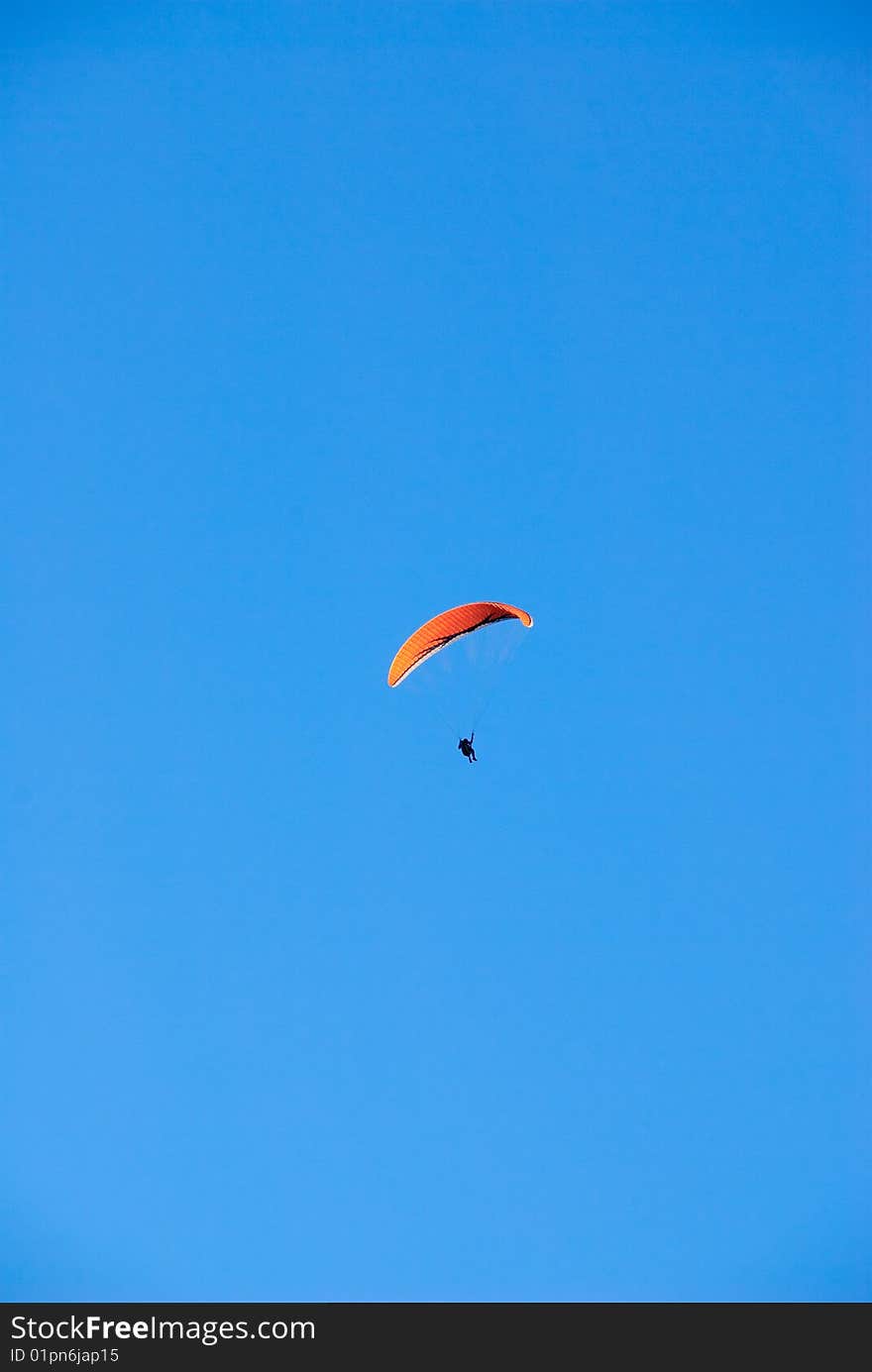 A parasailer in a bright blue sky. A parasailer in a bright blue sky