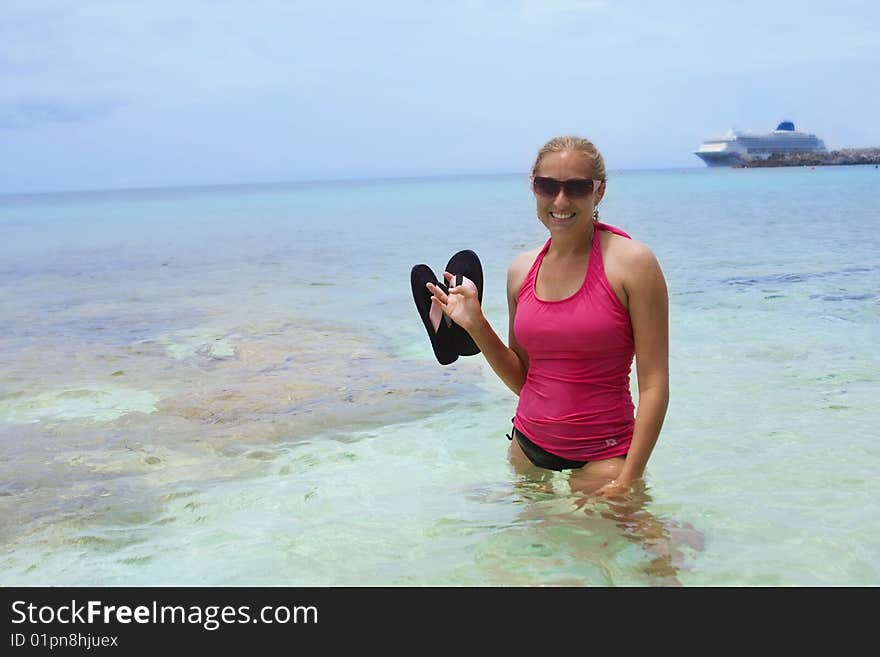 A woman enjoys her Caribbean Cruise vacation. Cruise ship is seen in the background