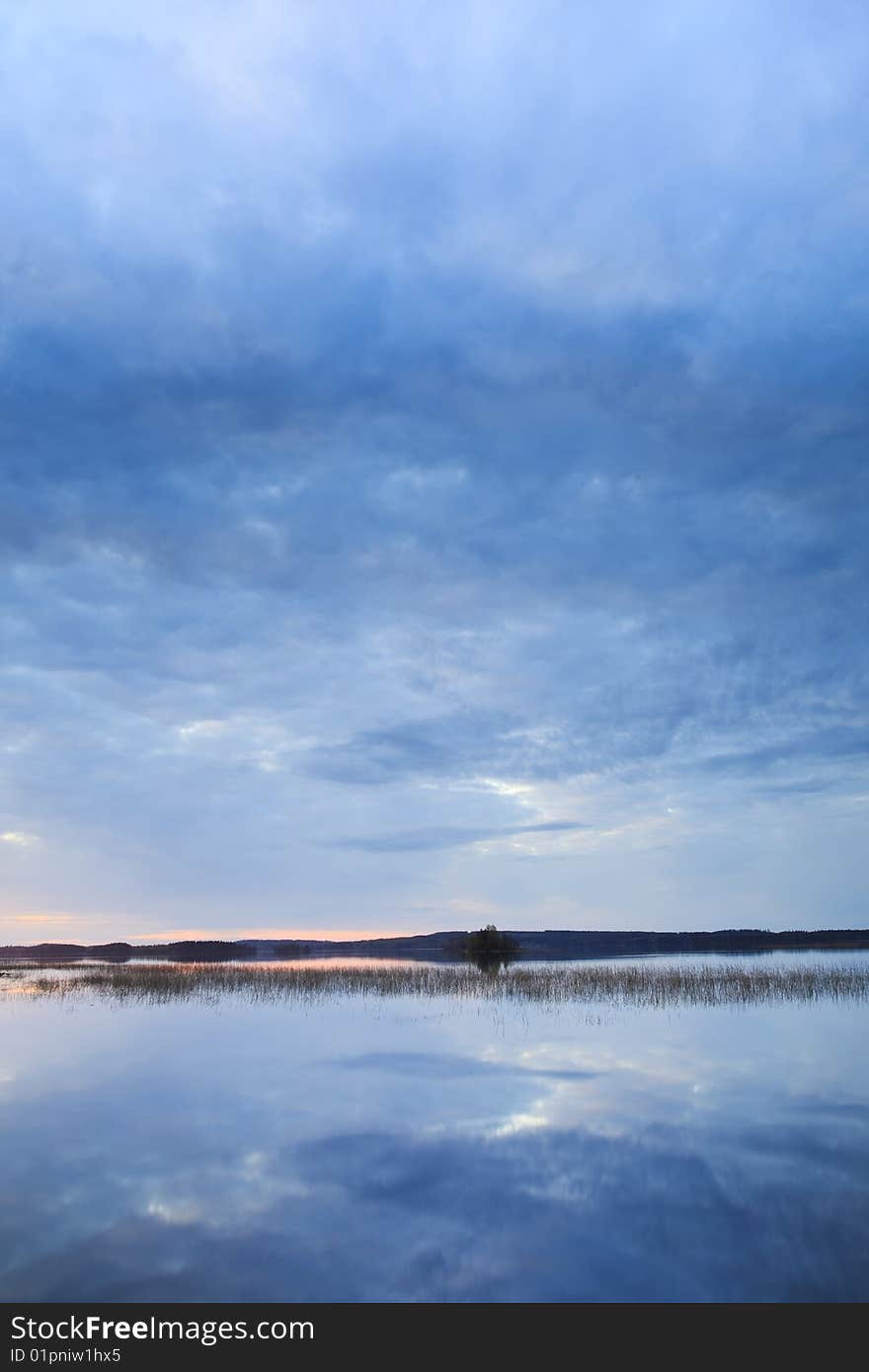 Sunset at calm lake with blue clouds from Finland. Sunset at calm lake with blue clouds from Finland