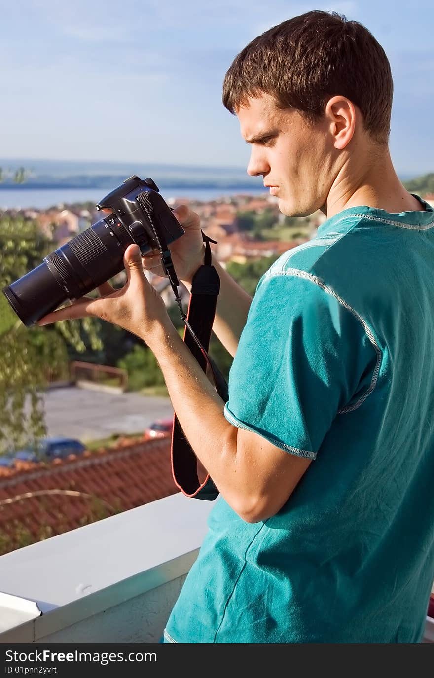 Young photographer checking new photographs on display of his digital slr camera