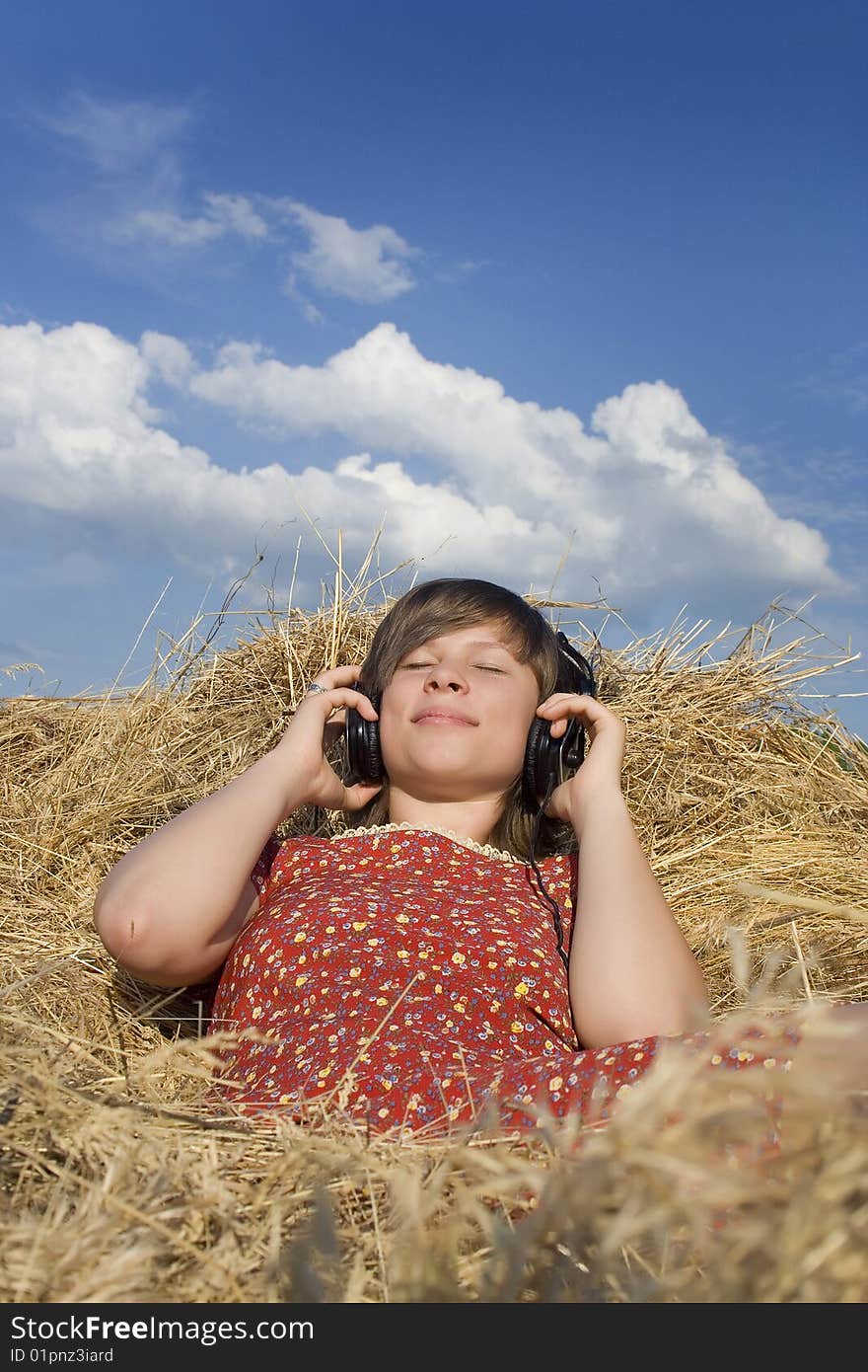 Young girl listenning to music in a stack of hay