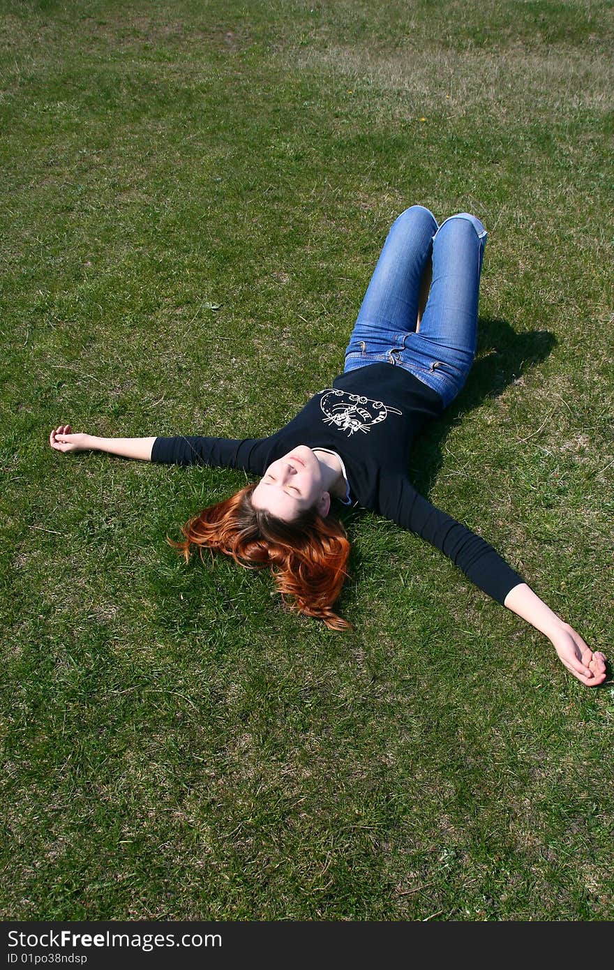 The girl lying on the grass exposing her face to the sun. The girl lying on the grass exposing her face to the sun