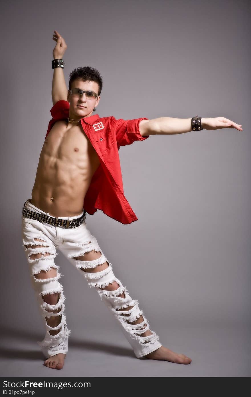 Young fashion man model with athletic body posing in sun glasses