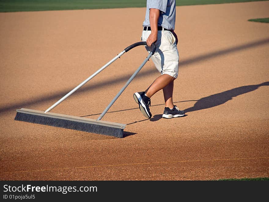 A young man prepares a baseball field for the game. A young man prepares a baseball field for the game.