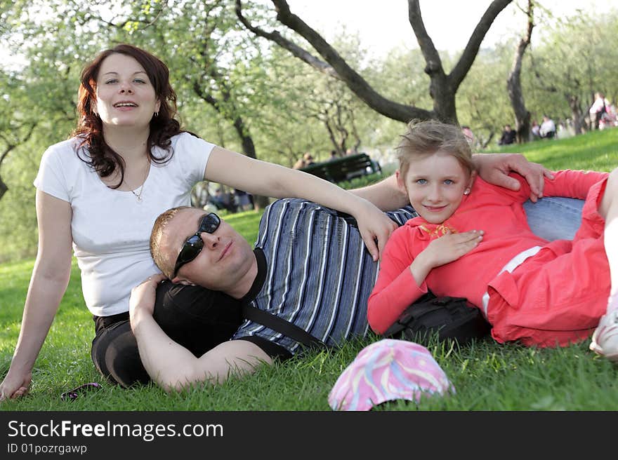 Happy family poses on green lawn in park