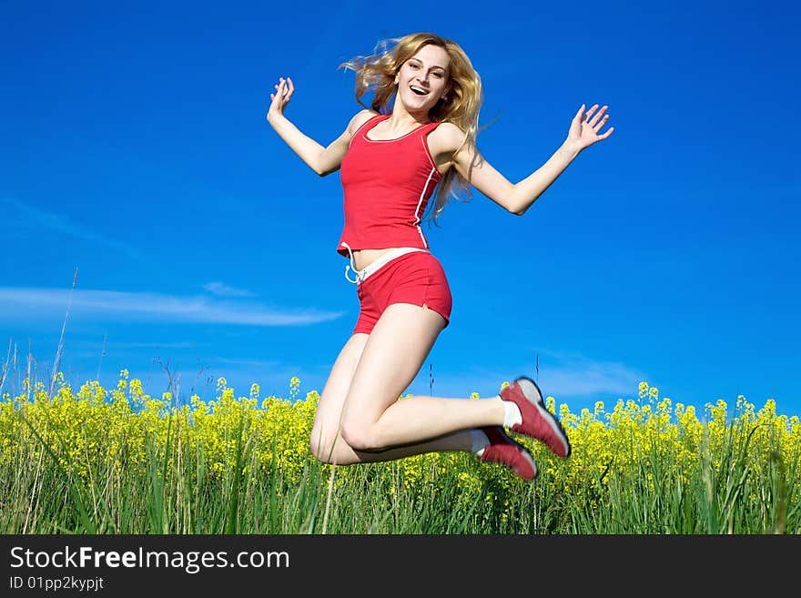 An image of a young girl jumping on a background of blue sky. An image of a young girl jumping on a background of blue sky