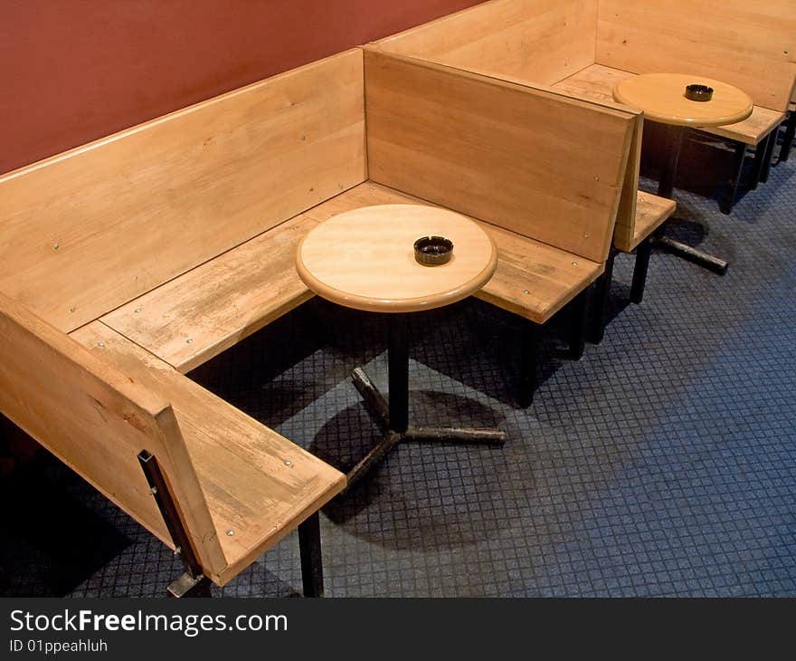 Plunk bench and round wooden tables with ashtray in cafe. Plunk bench and round wooden tables with ashtray in cafe