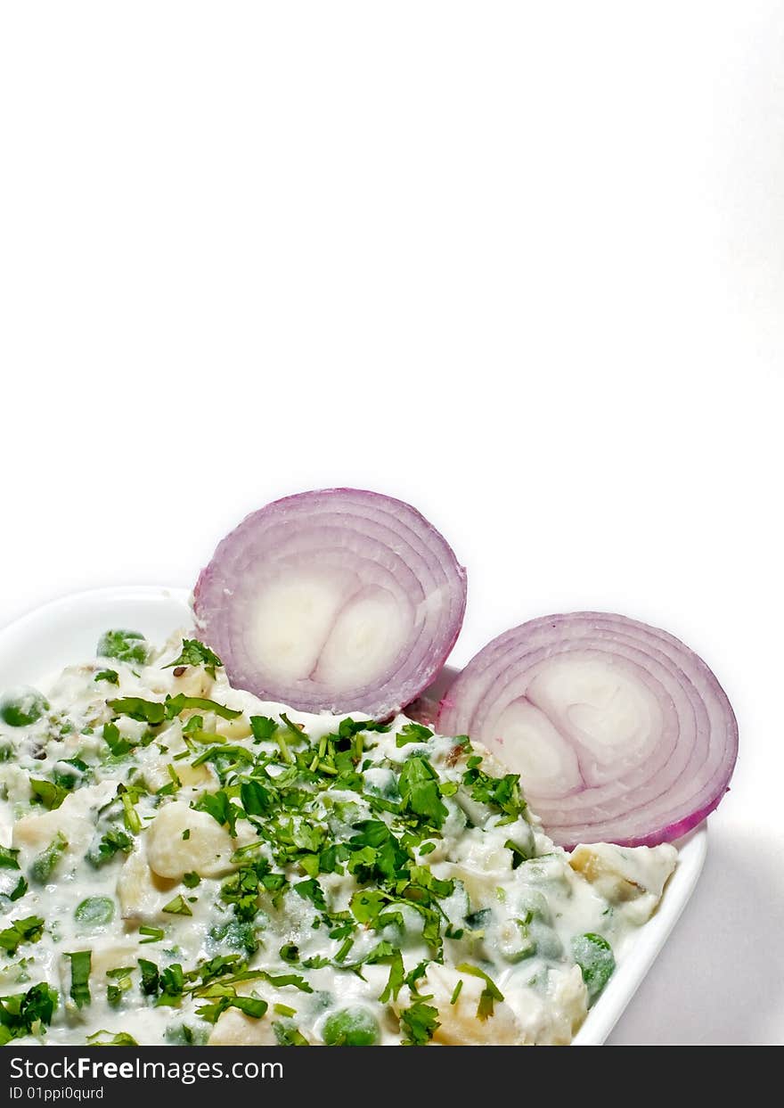 Baked vegetable in a whit bowl and two onions