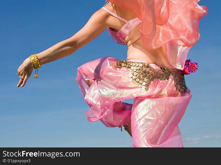 A woman in asian dress dancing close-up and a blue sky. A woman in asian dress dancing close-up and a blue sky