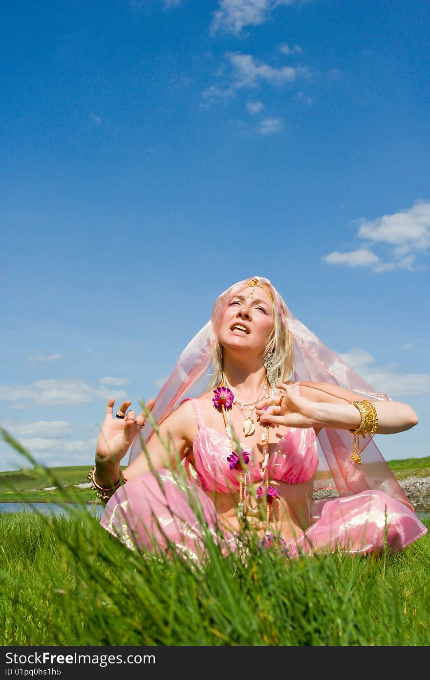 A woman in pink asian dress singing on the ocean shore