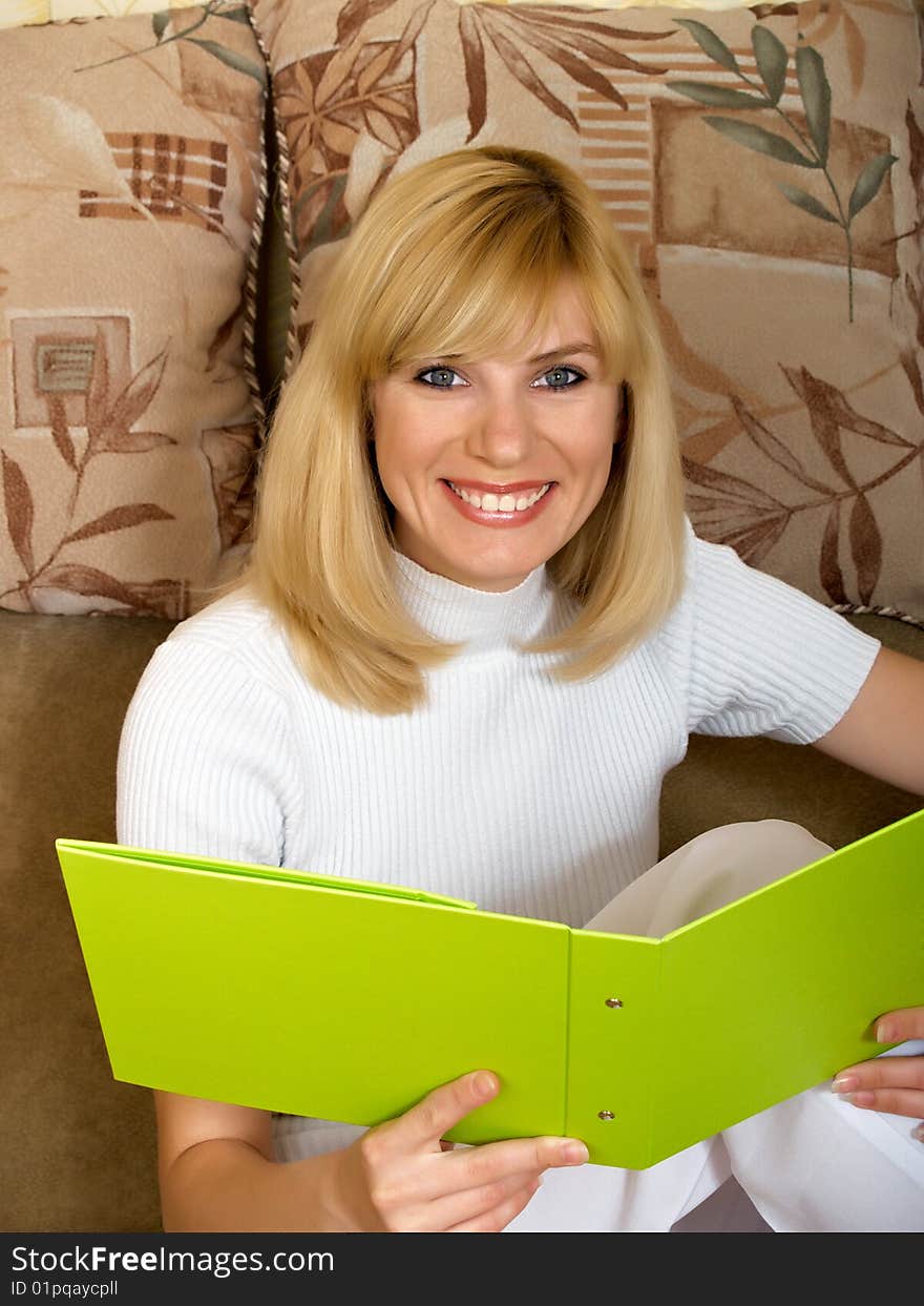 The beautiful girl sits at home with a folder for documents. The beautiful girl sits at home with a folder for documents