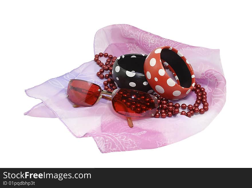 Female costume jewellery and the sun glasses laying on a gentle, pink scarf, represented on the isolated white background. Female costume jewellery and the sun glasses laying on a gentle, pink scarf, represented on the isolated white background