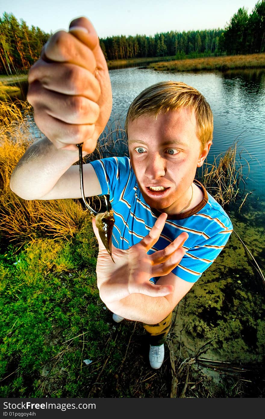 A cute guy showing off a crucian he has just caught. A cute guy showing off a crucian he has just caught