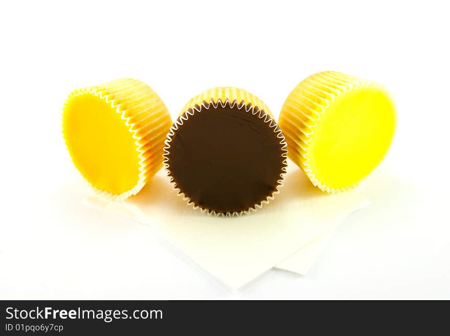 Three delicious looking cup cakes resting on two white napkins on a plain background. Three delicious looking cup cakes resting on two white napkins on a plain background