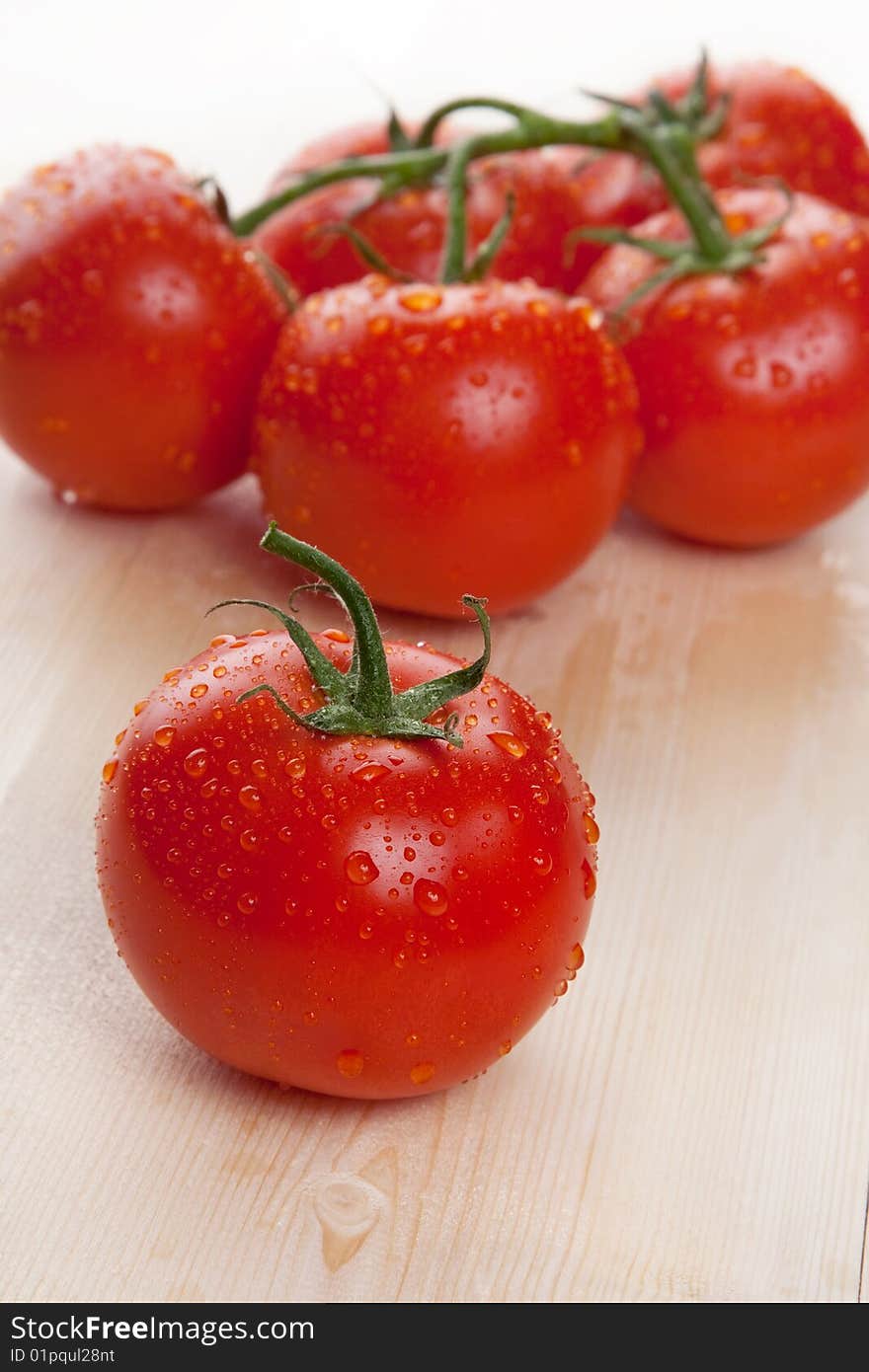 Red fresh group of tomatoes lay on wooden table isolated in studio