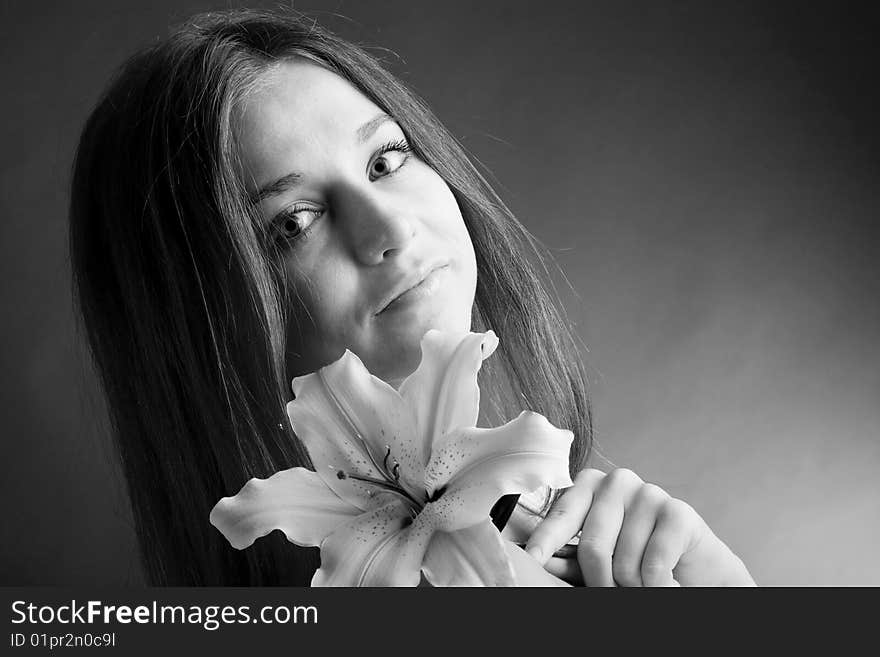 A pretty young woman with long hair posing with a lily in her hand. A pretty young woman with long hair posing with a lily in her hand