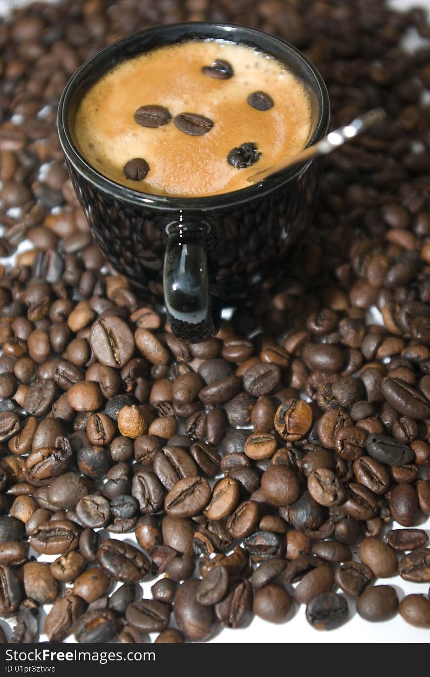 Cup of coffee between the coffee beans, to serve.