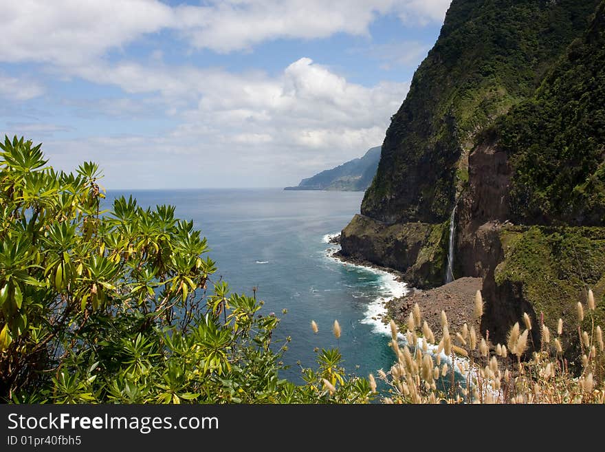 A picture of a mountain coast view with a waterfall coming out of the mountain. This picture is taken in Madeira Portugal. A picture of a mountain coast view with a waterfall coming out of the mountain. This picture is taken in Madeira Portugal