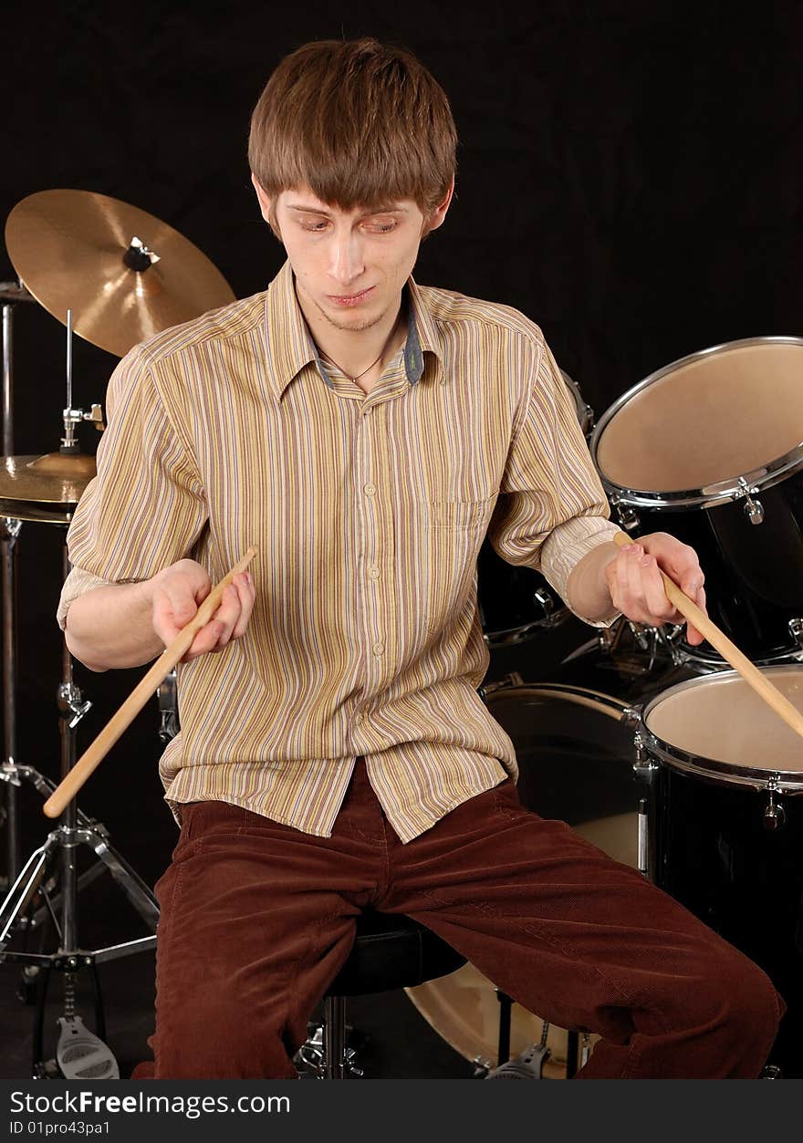 Young musician playing drums on black. Young musician playing drums on black.