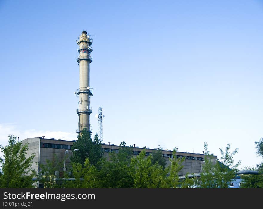 Generic view of a factory with a tall chimney and clear blue sky.