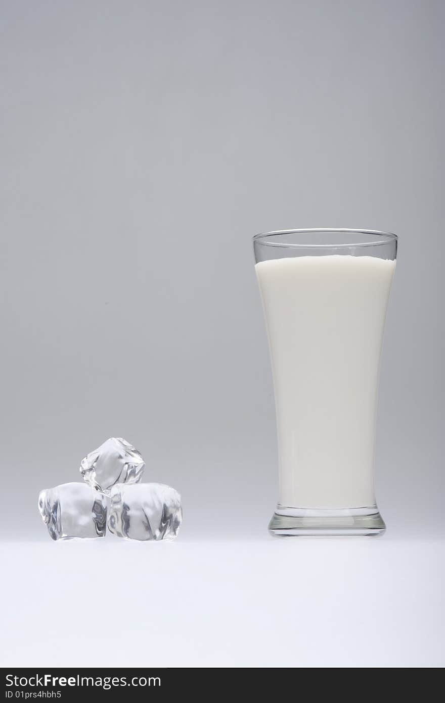 A glass of milk with ice on gray  background. A glass of milk with ice on gray  background