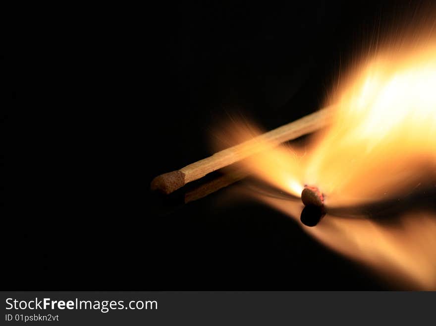 A match bursting into flames, isolated on a black reflective surface