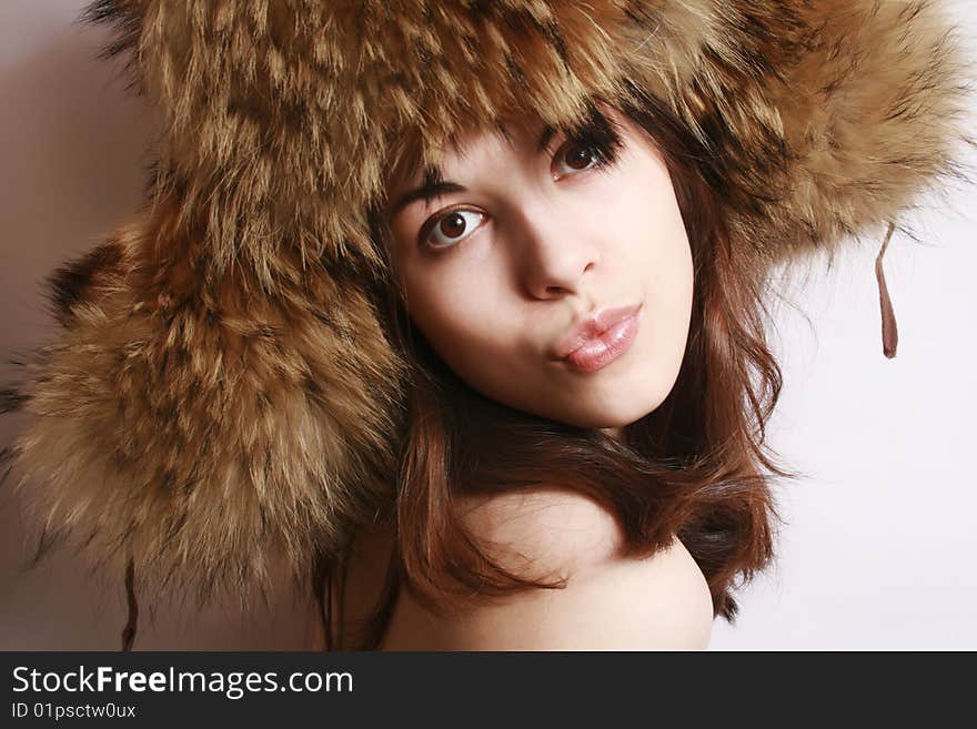 Portrait of the beautiful girl in a fur cap close up.