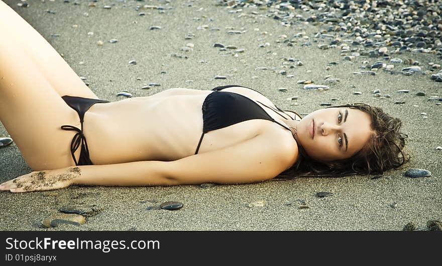 Laying beauty wearing black small bikini.