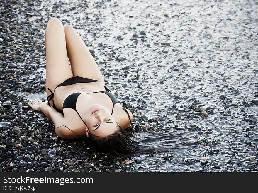 Laying green eyed beauty wearing black small bikini. Laying green eyed beauty wearing black small bikini.