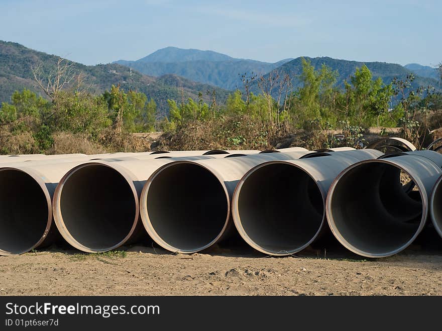 Rows of drainge sewage pipes with mountain background. Rows of drainge sewage pipes with mountain background