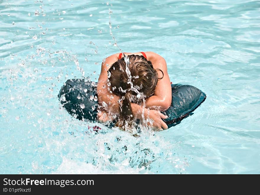 Young girl playing in a pool and being splashed by her playmate. Young girl playing in a pool and being splashed by her playmate.