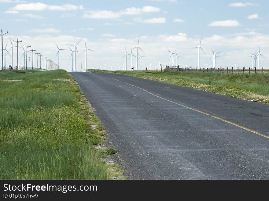 A wind farm on the horizon in Texas with heat waves from the highway