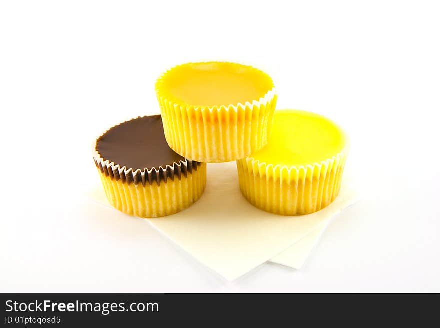 Three delicious looking cup cakes resting on two white napkins on a plain background. Three delicious looking cup cakes resting on two white napkins on a plain background