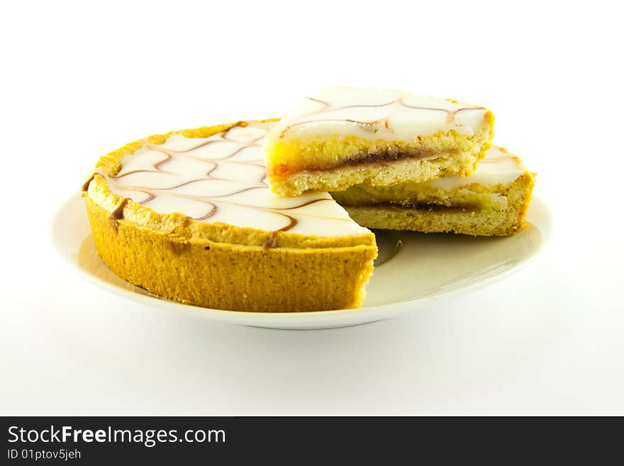 Delicious looking iced bakewell tart on a white plate with a plain background