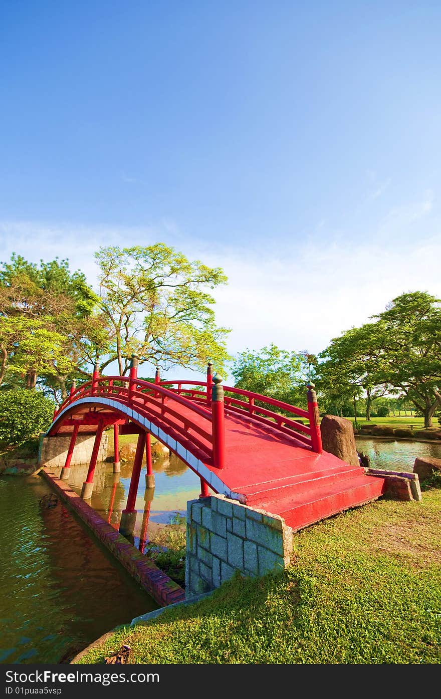 A red bridge panning across the lake in an ancient Chinese garden. A red bridge panning across the lake in an ancient Chinese garden.